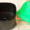 A black AirFryerMate: The Eco-Friendly Silicone Grill Tray Protector next to a green bag. (Brand: Martify)